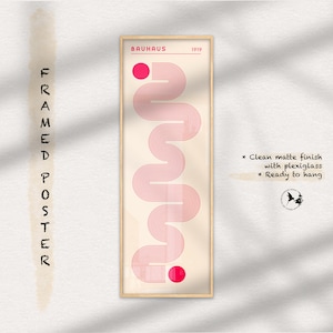 May include: A framed poster with a minimalist design featuring a pink abstract shape on a cream background. The poster is titled "Bauhaus 1919" and is ready to hang.
