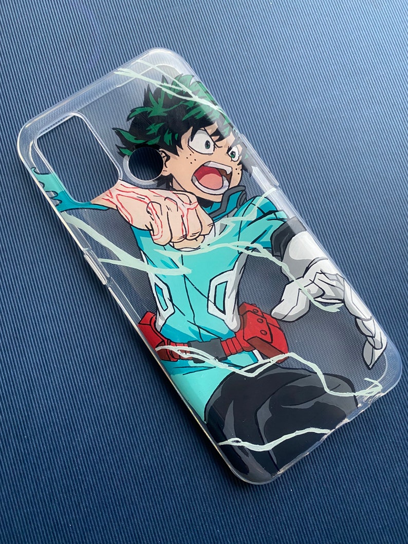 Peut inclure: Coque de t&eacute;l&eacute;phone transparente avec une illustration dynamique d'un personnage aux cheveux verts et une tenue bleu sarcelle et noire. Le personnage est en pleine action, avec des lignes d'&eacute;nergie blanches. La coque a une ceinture rouge et des gants blancs.