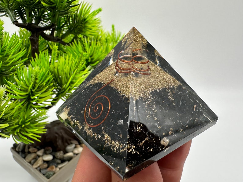 May include: Black obsidian pyramid with copper wire spirals and gold flecks. The pyramid is a crystal healing tool.