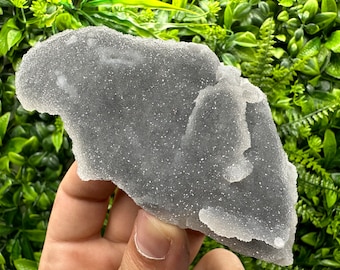 May include: A large, gray, translucent, crystal cluster with a rough, textured surface. The crystal is irregularly shaped and has a unique, organic form.