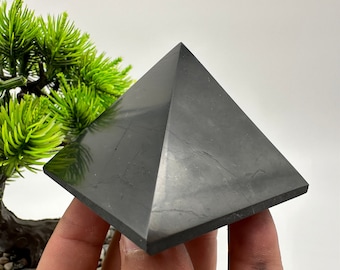 May include: A black obsidian pyramid, a smooth, polished crystal with a dark, reflective surface.