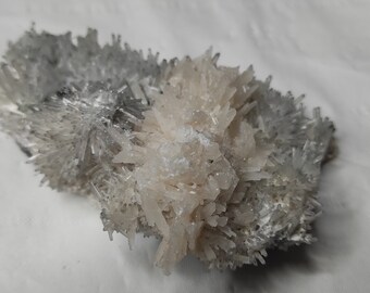 May include: A cluster of white and light pink crystals with a rough, natural texture. The crystals are arranged in a random, organic pattern, creating a unique and interesting display.