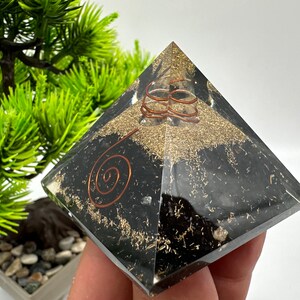 May include: Black obsidian pyramid with copper wire spirals and gold flecks. The pyramid is a crystal healing tool.