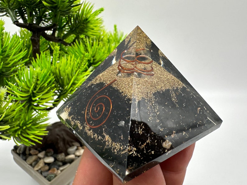 May include: Black obsidian pyramid with copper wire spirals and gold flecks. The pyramid is a crystal healing tool.