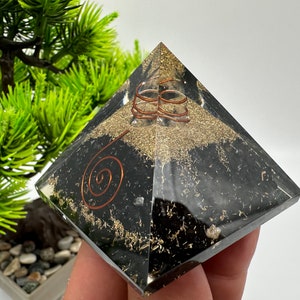 May include: Black obsidian pyramid with copper wire spirals and gold flecks. The pyramid is clear and has a polished finish.