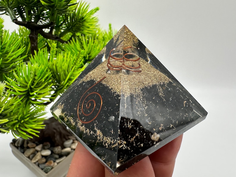 May include: Black obsidian pyramid with copper wire spirals and gold flecks. The pyramid is clear and has a polished finish.