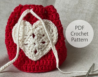May include: A red crochet heart-shaped drawstring bag with a white crochet heart design. PDF Crochet Pattern.