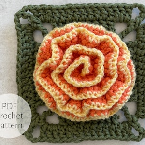 May include: A crochet flower pattern in PDF format. The flower is a multi-layered, orange and yellow crocheted flower with a green crocheted square border.