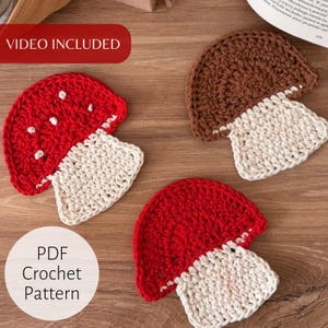 May include: Three crocheted mushroom appliques, two in red with white spots and one in brown, each featuring a cream-colored stem. The items are presented as a PDF crochet pattern with a video included, showcasing the textured yarn work.