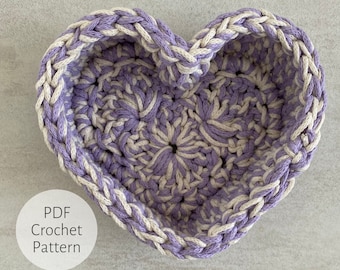 Peut inclure: Un panier en forme de cœur crocheté avec un motif de couleur violet et blanc. Le panier est fait avec un fil épais et a un motif texturé. Le texte "PDF Crochet Pattern" est visible dans le coin inférieur gauche de l'image.