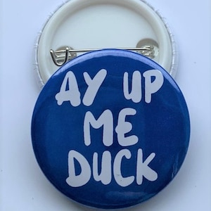 May include: A blue button with white text that reads "Ay Up Me Duck".