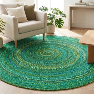 Può includere: Un tappeto rotondo intrecciato caratterizzato da un vivace gradiente di toni verdi, verde acqua e gialli. Il tappeto è realizzato con cerchi concentrici di fibre intrecciate, creando una superficie strutturata e multicolore sul pavimento.