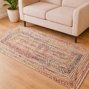 Könnte beinhalten: Rechteckiger Jute-Teppich mit geometrischem Muster. Der Teppich hat eine beige Basis mit farbenfrohen gewebten Akzenten in Rot-, Blau-, Gelb- und Grüntönen. Der Teppich liegt auf einem Holzboden.