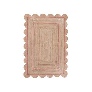May include: A natural fiber rug with a pink border and scalloped edges. The rug has a woven texture and a rectangular shape.