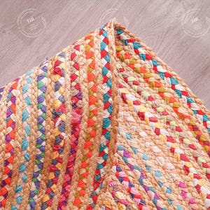 K&ouml;nnte beinhalten: Nahaufnahme eines farbenfrohen geflochtenen Jute-Teppichs. Der Teppich weist eine Mischung aus leuchtenden Farben auf, darunter Rot, Orange, Blau und Lila. Die Textur des Teppichs ist sichtbar und zeigt die Naturfasern und das komplizierte Webmuster.