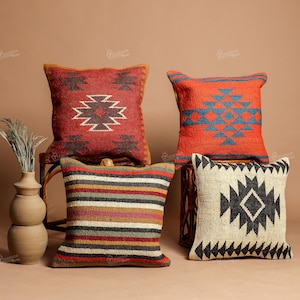 Puede incluir: Cuatro cojines decorativos con patrones geométricos. Los cojines presentan una variedad de colores, incluyendo rojo, naranja, negro y crema. Un cojín tiene un patrón de rayas, mientras que los otros tienen diseños geométricos.