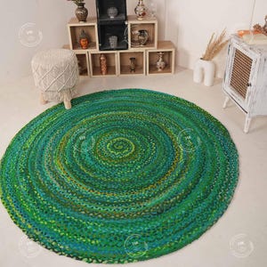 Puede incluir: Una alfombra redonda de yute trenzado de color verde y azul con un patrón circular. La alfombra está hecha de fibras naturales y tiene un estilo rústico y bohemio.
