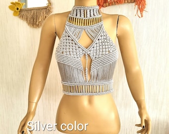 May include: A silver macrame halter top with a gold beaded trim. The top is crocheted with a geometric pattern and has a keyhole opening in the front. "Silver color" is written below the top.