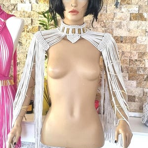 May include: White crocheted shoulder piece with fringe and a matching white crocheted choker necklace with gold accents.