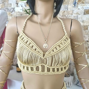 Op de afbeelding: Een gouden gehaakte top en rok set met een franje detail. De top heeft een halter-stijl halslijn en de rok is maxi lang.