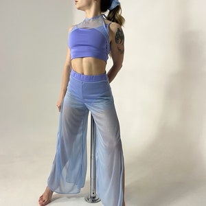 May include: A light blue mesh top and matching pants with a high waist and side slits. The top has a halter neck and a mesh panel across the chest. The outfit is worn by a person standing next to a silver pole.