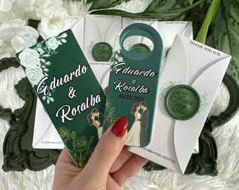 May include: A dark green bottle opener and a matching rectangular card featuring white floral illustrations, the text Eduardo & Rosalba, and the date 09/20/2025. The set includes white envelopes sealed with a green wax stamp reading Thank You.