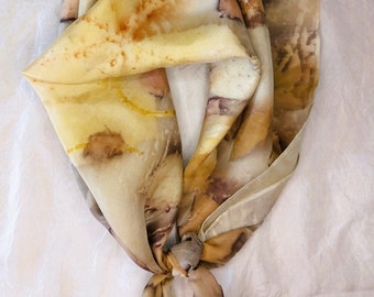 May include: A brown and yellow silk scarf with a tie-dye pattern. The scarf is folded and tied in a knot.