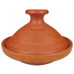 May include: A terracotta tagine pot, featuring a conical lid and a wide, shallow base. The earthenware pot is a warm reddish-brown colour, with visible texture from the clay. The lid has a rounded handle. This traditional cooking vessel is designed for slow-cooked stews.