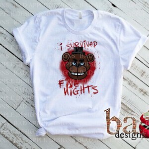 May include: White t-shirt featuring a graphic of a brown bear with a black top hat and the text "I survived five nights" in red. The bear is set against a red splatter background. The shirt has rolled-up sleeves.