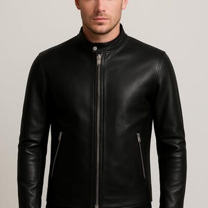 Puede incluir: Chaqueta de cuero negra con cuello alzado y cremallera completa. La chaqueta tiene dos bolsillos con cremallera en la parte delantera y un corte entallado. El modelo lleva pantalones negros.