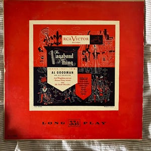 Puede incluir: Una portada de álbum vintage de RCA Victor Records en rojo, con "The Vagabond King". La portada tiene ilustraciones y texto en blanco y negro, incluyendo "Long 33 1/3 Play."