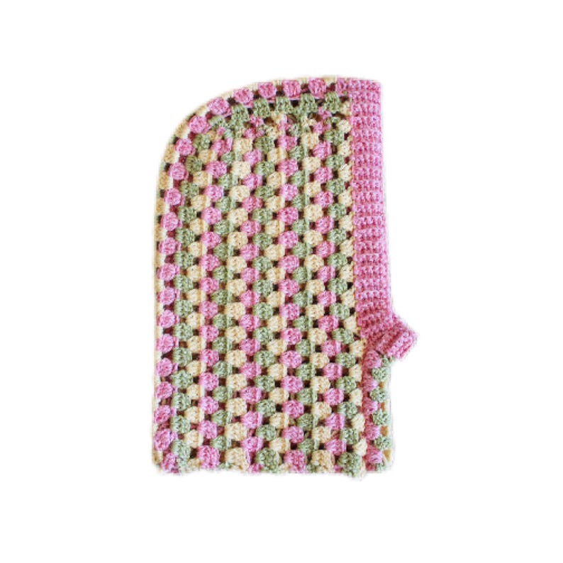 Op de afbeelding: Een gehaakte sjaal met capuchon in de kleuren roze, groen en cr&egrave;me. De sjaal is gemaakt met een granny square steekpatroon.