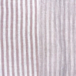 May include: A textile fabric featuring a vertical striped pattern in muted mauve and white. The left side displays wider, soft-edged stripes, while the right side transitions into a denser, finer arrangement of the same mauve and white vertical stripes.