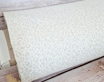 May include: A roll of fabric featuring a repeating leopard print pattern in soft beige and off-white tones. The textile has a subtle ribbed texture throughout, showcasing a consistent animal-inspired design across the entire surface of the material.