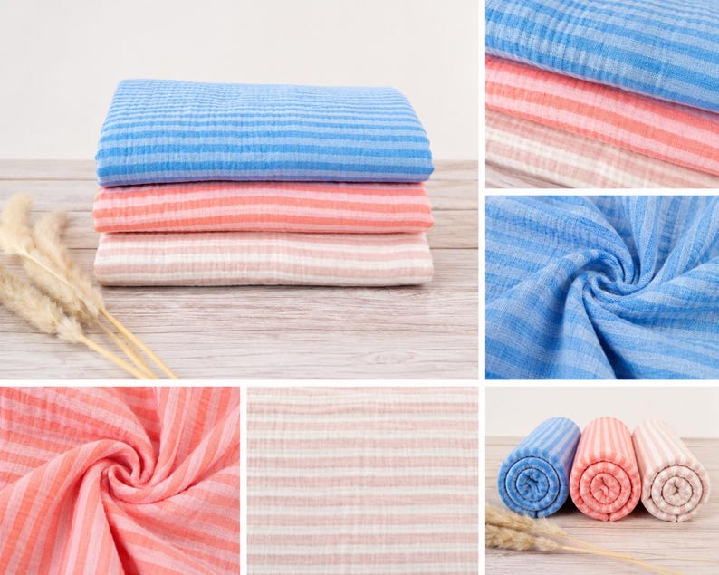 May include: A collection of soft, crinkled muslin fabric pieces featuring horizontal stripes in shades of blue, coral, and light pink. The fabric is shown both folded in neat stacks and rolled into cylinders, displaying a lightweight, textured weave.