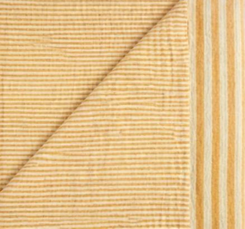 May include: A textile fabric featuring a textured, crinkled surface with a pattern of thin, horizontal mustard yellow and white stripes, transitioning into a border of wider, vertical mustard yellow and white stripes along the right edge.