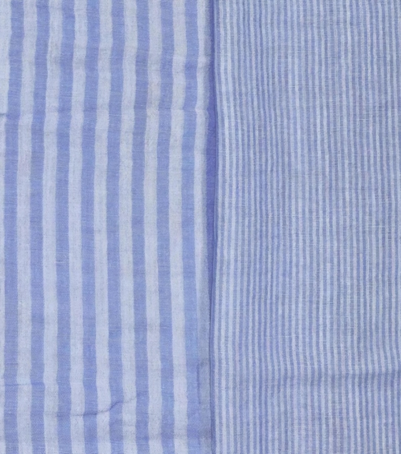 May include: A textile fabric featuring two distinct sections of vertical stripes. The left side displays wide, alternating light blue and white stripes, while the right side shows a pattern of much finer, narrow light blue and white vertical stripes.