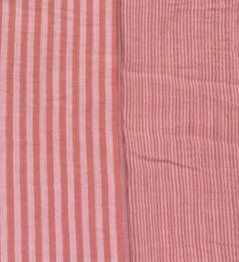 May include: A textile fabric featuring two distinct sections of striped patterns. The left side displays wide vertical stripes in alternating shades of coral and light pink, while the right side shows a finer, denser vertical stripe pattern in similar tones.