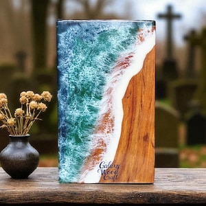 May include: A rectangular wooden art piece with a resin ocean wave design. The artwork features a vibrant blue and green wave crashing onto a wooden beach. The text "Galaxy Wood Craft" is visible on the lower right corner.