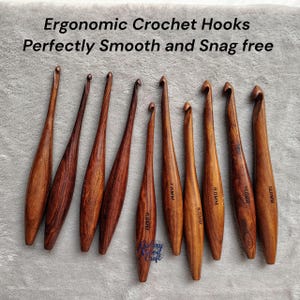 May include: A collection of ergonomic crochet hooks made of wood. The hooks vary in size, with measurements from 6.5MM to 12.0MM. The text on the image reads "Ergonomic Crochet Hooks Perfectly Smooth and Snag free."