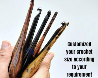 Könnte beinhalten: Eine Sammlung von Häkelnadeln aus Holz in verschiedenen Braun- und Schwarztönen, gehalten in einer Hand. Die Haken haben gebogene Enden und sind unterschiedlich groß. Der Text auf dem Bild lautet: "Customized your crochet size according to your requirement."