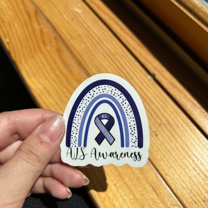 May include: A blue and white rainbow sticker with a blue ribbon and the text "ALS" and "ALS Awareness".