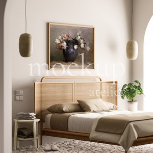 May include: A bedroom with a wooden bed frame with a woven headboard, a white duvet, and a brown throw blanket. There are two hanging lamps with woven shades, a painting of flowers in a vase, and a potted plant on a side table.