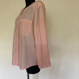 May include: A sheer peach button-down shirt with a single pocket on the left chest.