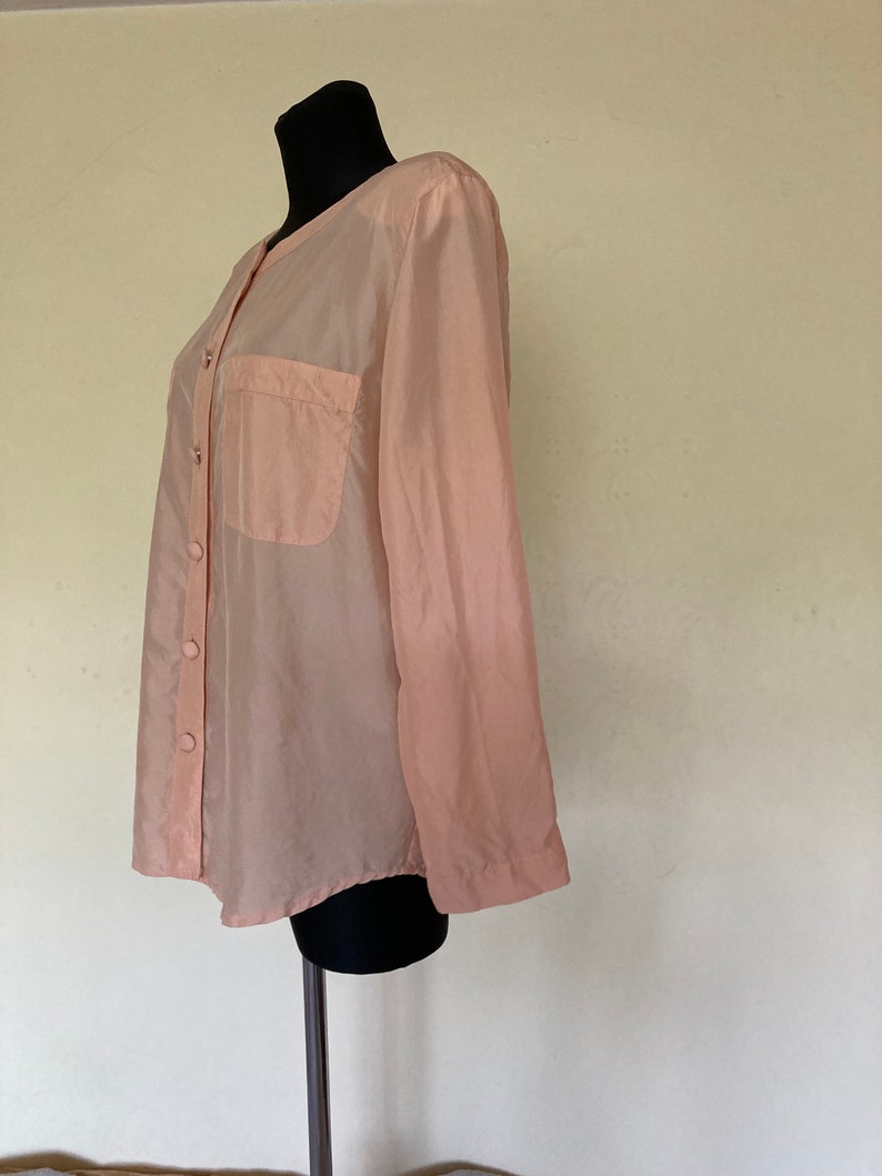 May include: A sheer peach button-down shirt with a single pocket on the left chest.