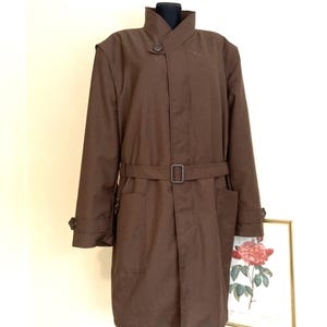 Pode incluir: Um casaco comprido marrom de manga comprida com gola alta e fecho de botão único.