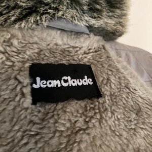 May include: A gray faux fur hooded jacket with a black label that reads "Jean Claude" on the back.