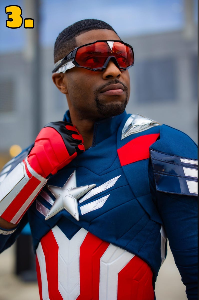 Pode incluir: Um traje inspirado no Capit&atilde;o Am&eacute;rica, com um esquema de cores azul e vermelho e uma estrela branca no peito. A pessoa tamb&eacute;m usa &oacute;culos vermelhos e luvas vermelhas e brancas. O traje tem detalhes prateados.