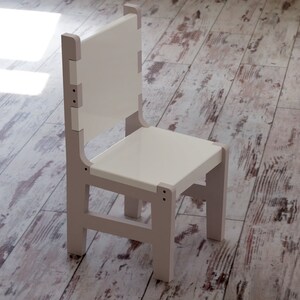 May include: A white wooden chair with a simple design. The chair has a rectangular seat and a tall back.