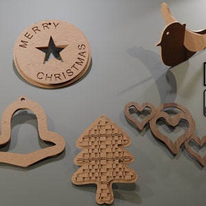 May include: Wooden Christmas ornaments in various shapes, including a bell, a tree, and hearts. One ornament is a circle with the words "MERRY CHRISTMAS" and a star cutout. A wooden bird is also present.